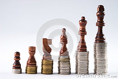 Black chess figures standing on coins meaning power and career growth. Stock Photo