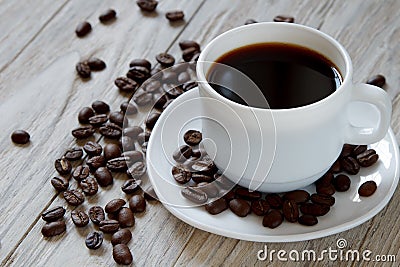 Black coffe and roasted beans in a white mug on wooden surface Stock Photo