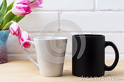 Black coffee cup and white latte mug mockup with magenta tulip Stock Photo