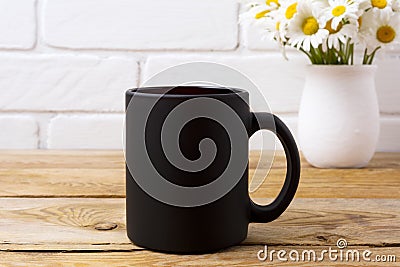 Black coffee mug mockup with chamomile bouquet in rustic vase Stock Photo