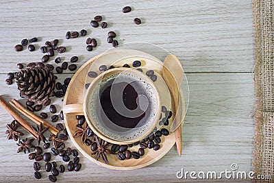 Black coffee in wooden cup and coffee beans spill on wooden background Stock Photo