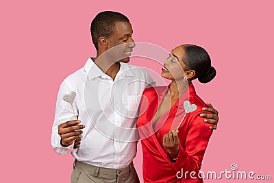 Black couple adoring each other, holding glitter hearts Stock Photo