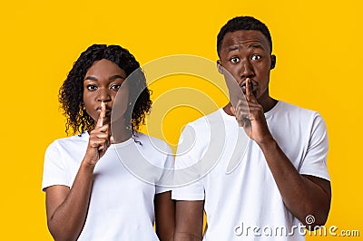 Black couple make silence sign, keep forefingers on lips Stock Photo
