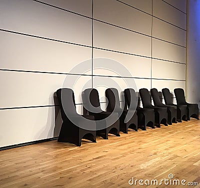 Black covered chairs against white wall on a modern wood stage Stock Photo