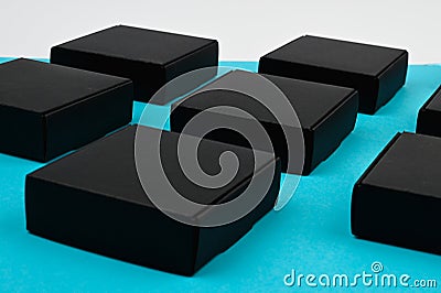 Black cubes side view. black boxes on blue. black boxes on a blue background on a flat lay. Black square on blue Stock Photo