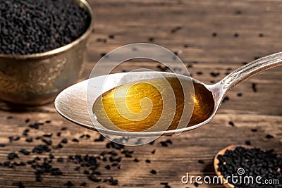 Black cumin seed oil on a spoon and black cumin seeds Stock Photo