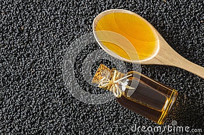 Black cumin seeds essential oil , Nigella Sativa in spoon on heap of black cumin Stock Photo