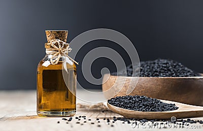 Black cumin seeds essential oil , Nigella Sativa in spoon on wooden background Stock Photo