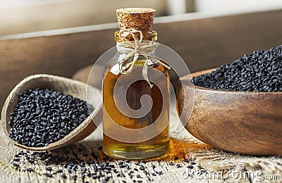 Black cumin seeds essential oil , Nigella Sativa in spoon on wooden background Stock Photo