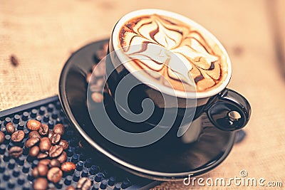 Black cup of freshly brewed espresso coffee. Close-up of coffee cup with milk and beans Stock Photo