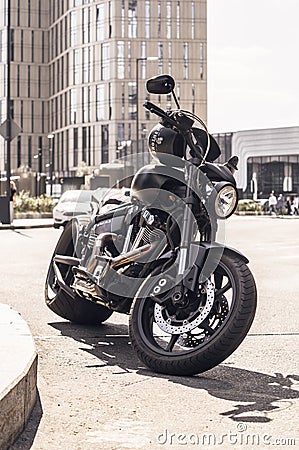 black custom motorbike parked in the street. Motorcycle chopper with a very wide rear wheel standing on the modern city buildings Editorial Stock Photo