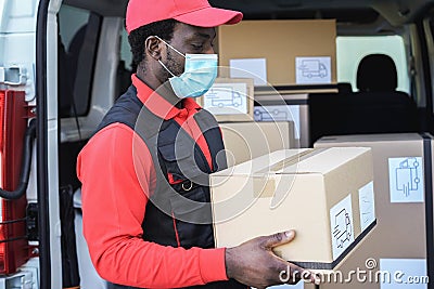 Black delivery man wearing safety mask for coronavirus prevention - Focus on face Stock Photo