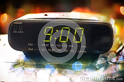 Black digital alarm radio clock.Alarm radio clock indicating time to wake up.Digital clock closeup displaying 9:00 o`clock.Digital Stock Photo