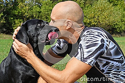 Black dog give kiss man Stock Photo