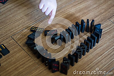 black dominoes heart shape pushing by finger hand on wooden background Stock Photo