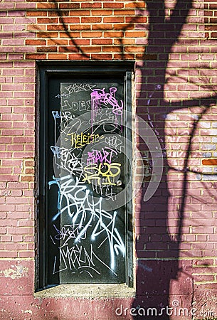 Black door with colored graffiti on a brick wall in a lane in Montreal Stock Photo