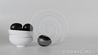 Black eggs fall from a white ceramic cup on a gray background. Stock Photo