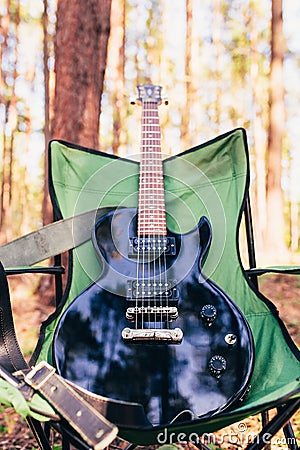 Black electric guitar in the woods - outdoor music - campfire guitar for songs and music by the campfire Stock Photo