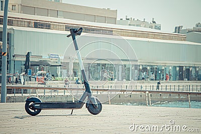 Black electric scooter parking on a deck at Tel Aviv Port commercial district on a summer sunny day Editorial Stock Photo