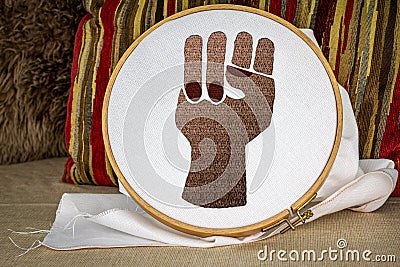 Black embroidered raised power fist on sewing hoop, activism through craft, craftivism, black lives matter, feminism, senior women Stock Photo