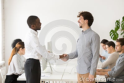 Black employer shaking hand of shy male Caucasian job applicant Stock Photo
