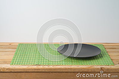 Black empty plate and bamboo placemat on wooden table. Chinese kitchen or restautant concept background Stock Photo