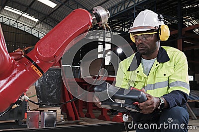 Black engineer test and control robotic arm in mechanical manufacturing factory Stock Photo