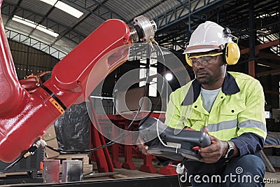 Black engineer test and control robotic arm in mechanical manufacturing factory Stock Photo