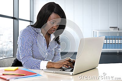 Black ethnicity woman sitting at computer laptop desk typing concentrated working Stock Photo