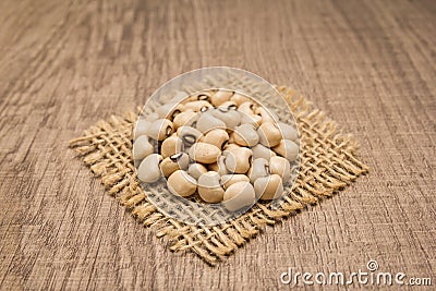 Black Eyed Pea legume. Grains on square cutout of jute. Wooden t Stock Photo