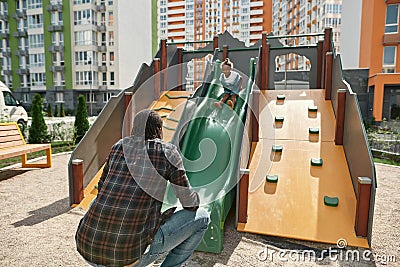 Black father catching daughter get down on slide Stock Photo