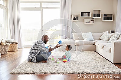 Black father and toddler son playing in sitting room Stock Photo