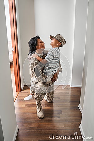 Black female soldier holds son on arms at home Stock Photo