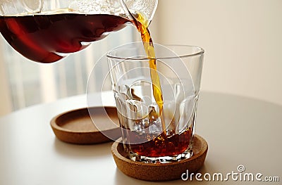 Black filter coffee pours from a jug into a glass close up. Specialty third wave concept Stock Photo