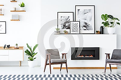 Black fireplace between grey armchairs in apartment interior wit Stock Photo