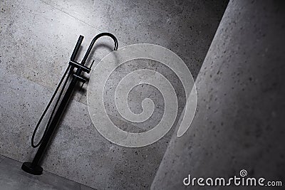 Black floor mounted mixer in dark grey bathroom. Stock Photo