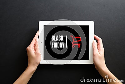 Black friday sale concept. Woman`s hands holding tablet pad with sign `Black friday` and shopping cart Stock Photo