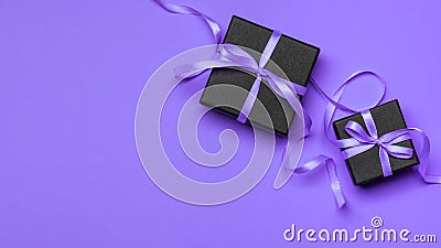 Black gift boxes tied with purple ribbons on a purple background Stock Photo