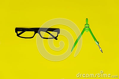 Black glasses and colorful green compasess for circle drawing in school or education colorful yellow background Stock Photo