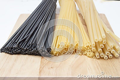 Black and golden spaghetti, pastes on a wooden board Stock Photo