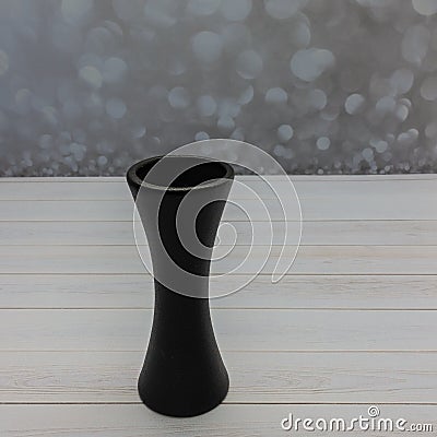 A black graceful ceramic flower vase stands on a wooden table Stock Photo