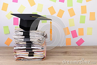 Black graduated cap and yellow tassel on stack documents,Colorful paper post it the background Stock Photo