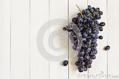 Black grape branch on white wooden background Stock Photo