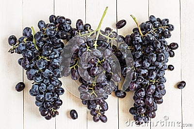 Black grape branch on white wooden background Stock Photo