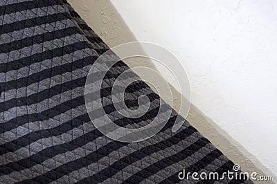 Black and gray quilted blanket against wall Stock Photo