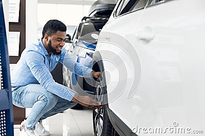 Black Guy Checking Car Wheels And Tyres In Dealership Showroom Stock Photo