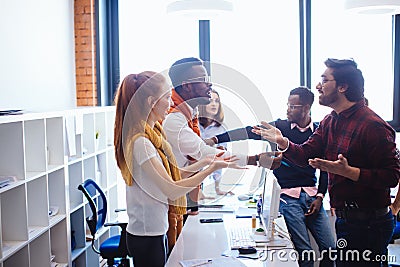 African and Hindu coworkers with their supporters arguing at work Stock Photo