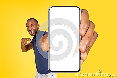 Black Guy Showing Cellphone With Huge Empty Screen, Yellow Background Stock Photo