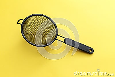 Black hand strainer isolated over a yellow background Stock Photo