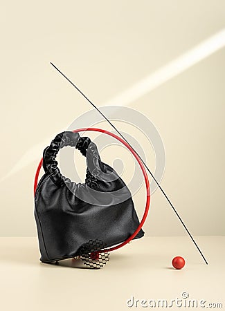 Black handbag made from an artificial leather on a beige background with sun`s rays. Idea of suprematism. Conceptual creative Stock Photo